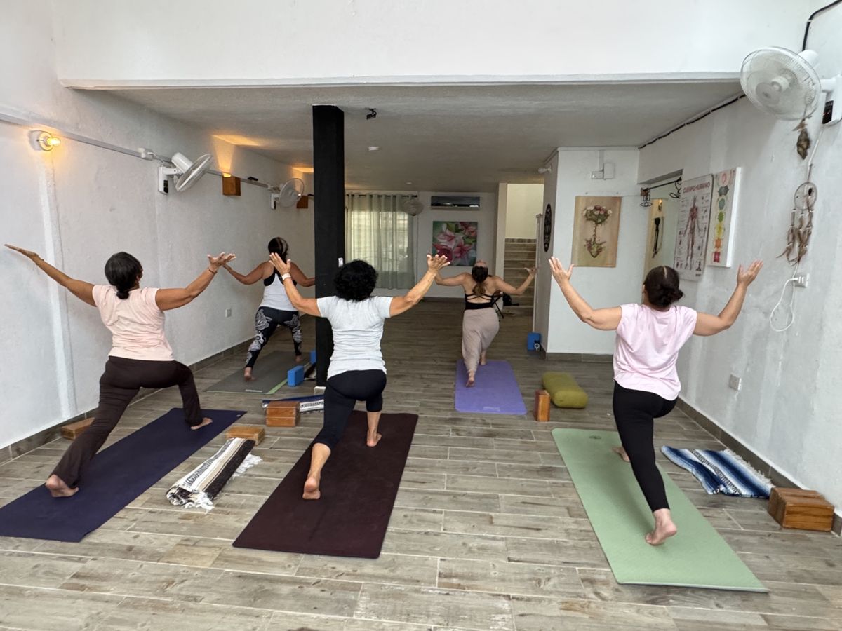 Grupo practicando yoga en el salón de Centro Florecer, visto desde atrás