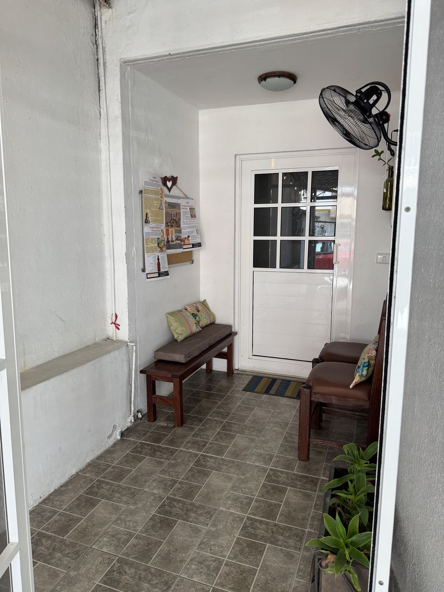 Recibidor de Centro Florecer con banca, sillas, pizarrón de carteles y puerta blanca