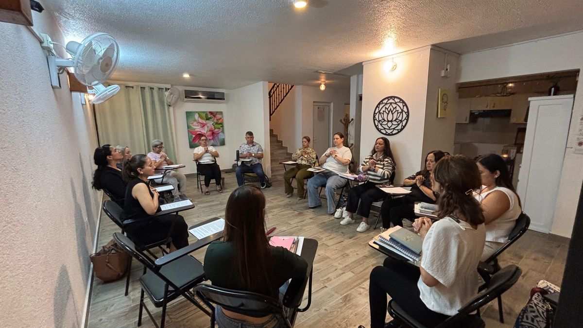 Participantes del taller sentadas en círculo con las manos en oración en el salón de Centro Florecer