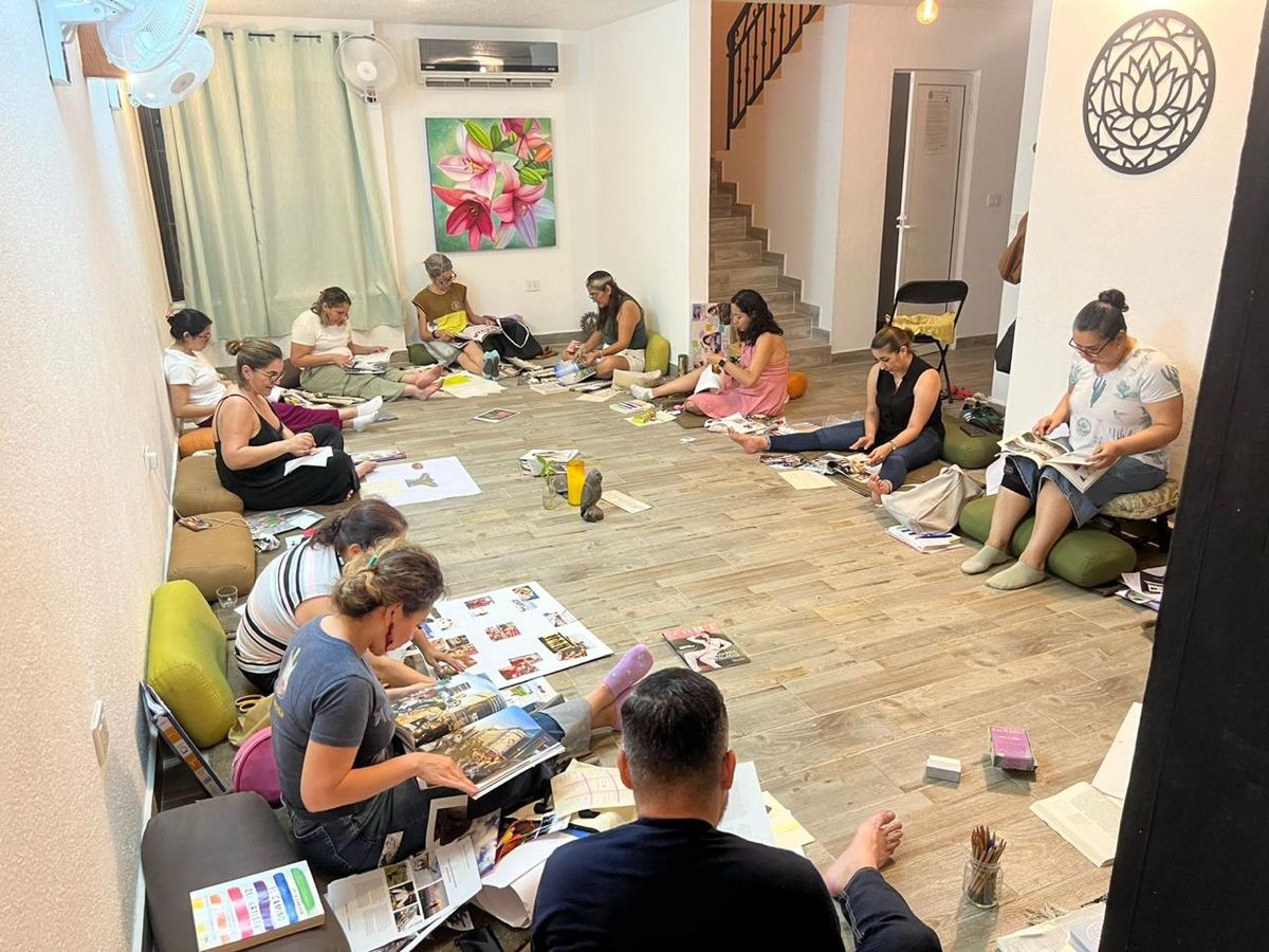 Participantes del taller trabajando con revistas, tijeras y cartulinas en el piso del salón